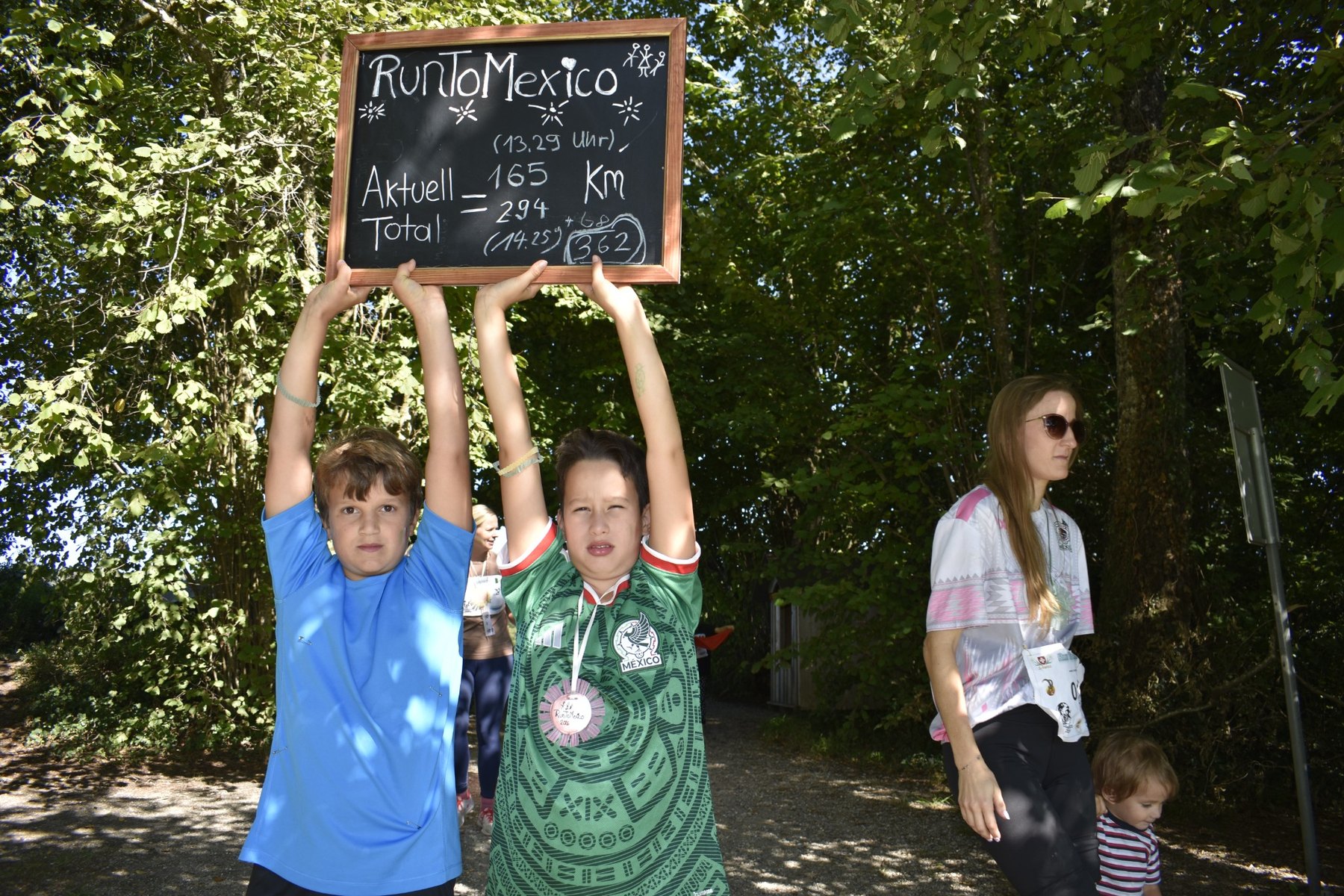 Kinder halten die RunToMexico Tafel mit dem Schlussstand von 362 Kilometern
